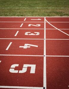 Close-up view of a red running track with numbered starting lanes, perfect for athletic themes.